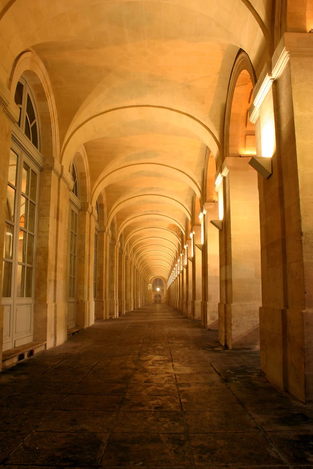 A long stone arcade under warm lamplight